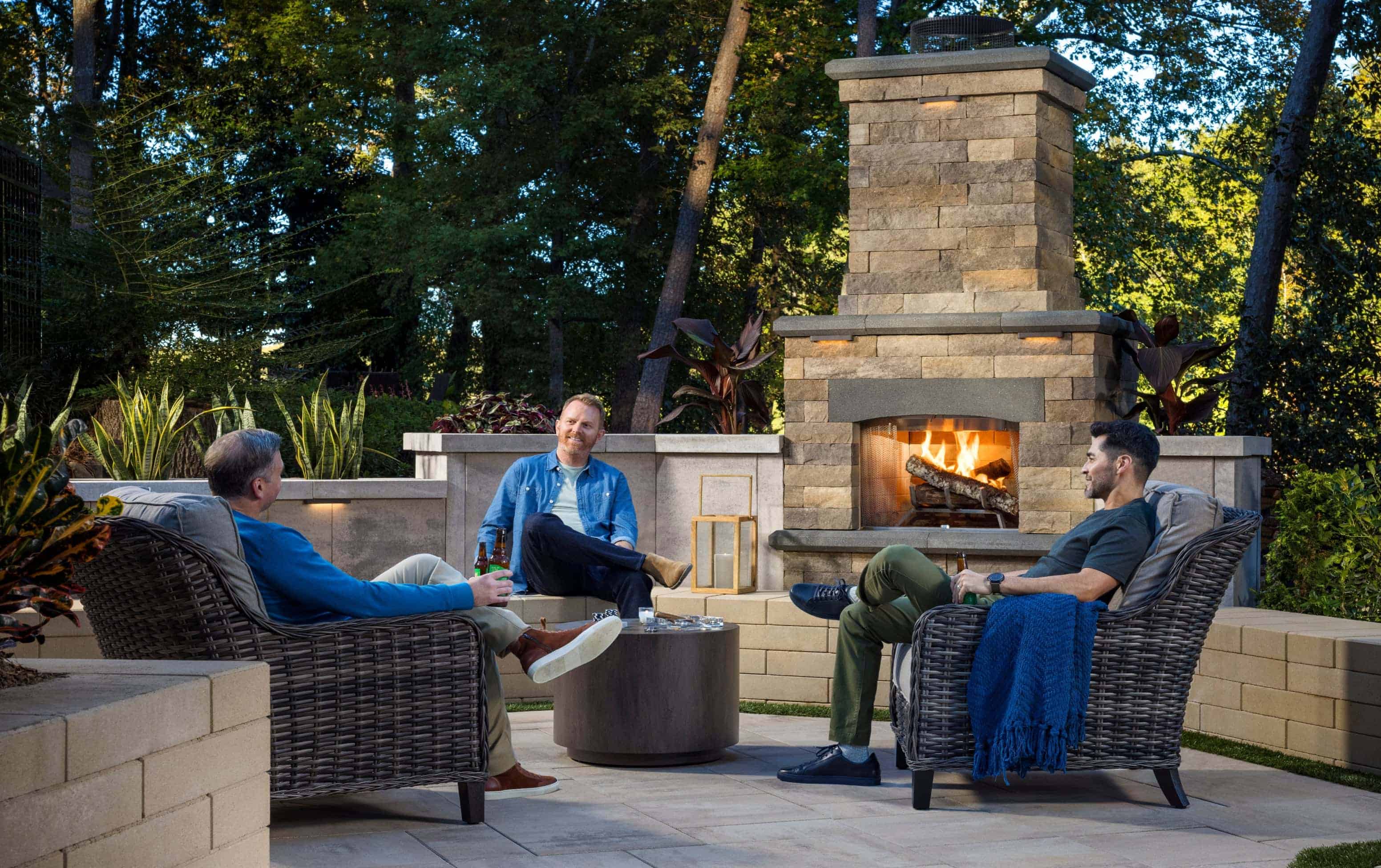 3 friends enjoying a conversation outside near a fireplace