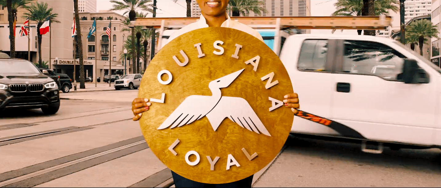Person holding a sign in New Orleans with the Louisiana Loyal logo