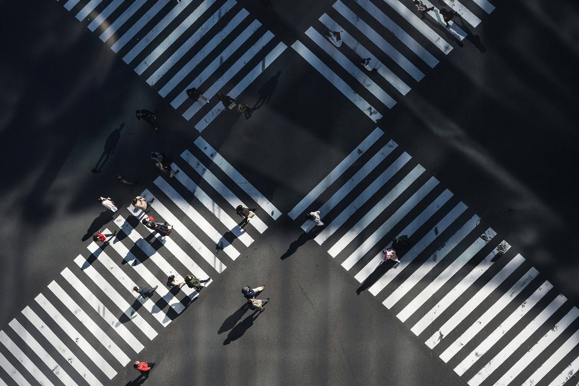 Groups of people going their separate ways as they cross a street.